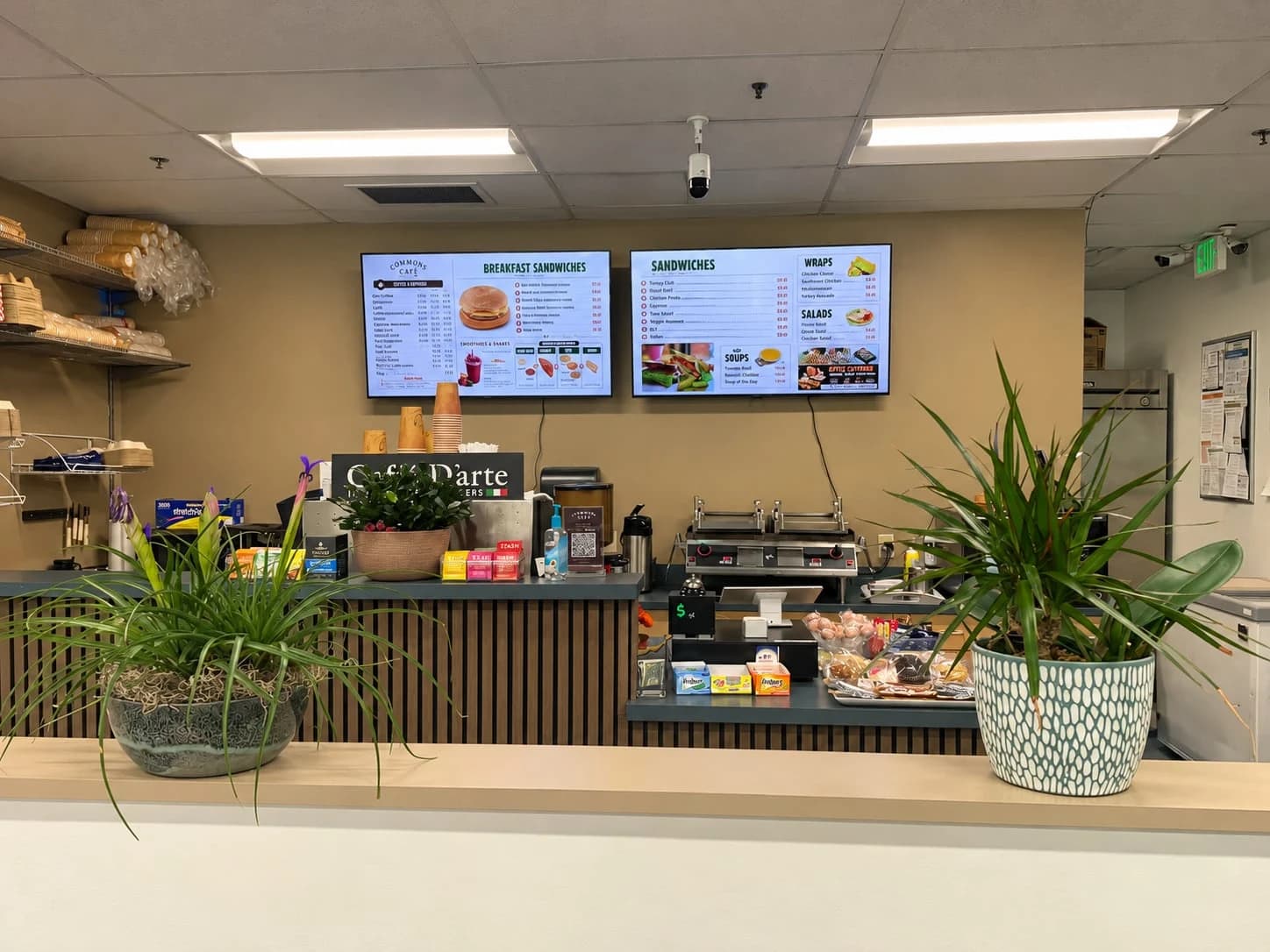 Commons Cafe service counter, coffee station, menu boards, and plants